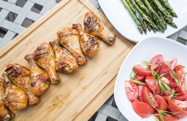 Barbecue Chicken Drumsticks Served with Roasted Asparagus and Tomato Salad