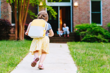 Happy Toddler girl arriving home from school with a backpack