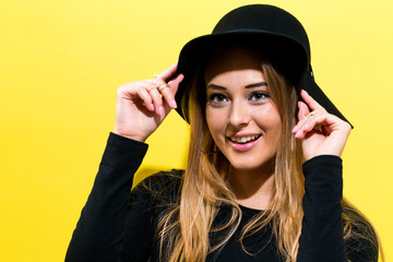 Happy young woman wearing a hat on a yellow background