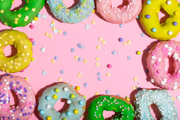 Colorful glazed donuts on a pink background