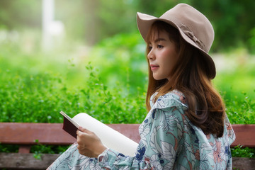 Beautiful asian woman relaxing by reading book in park