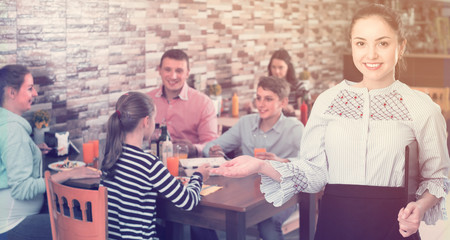 positive young waitress warmly welcoming guests to family cafe