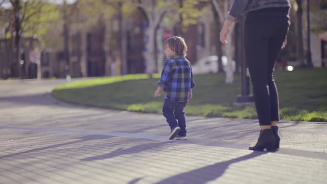 Little Boy Walks Ahead Of His Mother, She Follows Along 