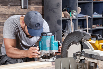 builder handles a wooden plank with a milling machine