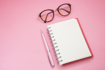 top view. pen putting beside blank notebook and have glasses on top side of notebook isolated on background. image for business,education,accessory,equipment concept