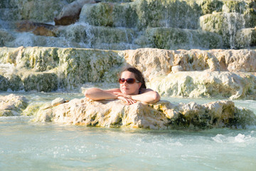 Junge, attraktive Frau genießt warmes Wasser in einer Therme in Saturnia, Toskana