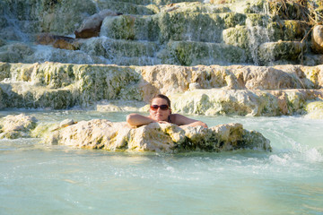 Junge, attraktive Frau genießt warmes Wasser in einer Therme in Saturnia, Toskana