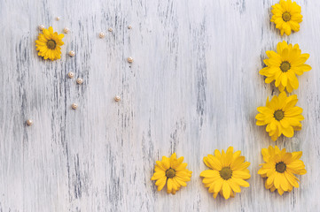 Wooden surface painted white with yellow flowers and beads of pearls. Beautiful background with chrysanthemums.