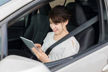 young woman using tablet PC on the seat of motor vehicle.