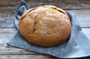 Fresh baked round  bread with linen napkin on wooden table.Rustic style food background.