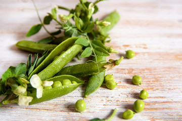 fresh green peas, peas flowers and leaves on wooden background, flat lay, top view 