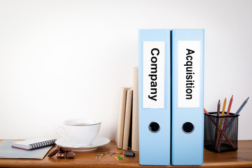 Company and Acquisition binders in the office. Stationery on a wooden shelf.