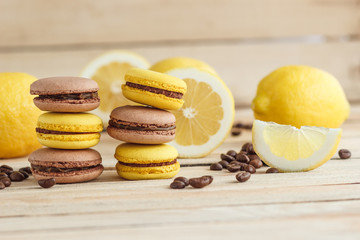 Yellow and brown french macarons with lemons and coffee beans on the wooden board