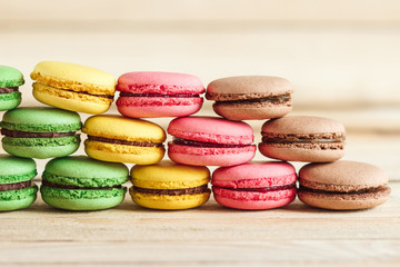 Obraz na płótnie Canvas Green, pink, yellow and brown french macarons on the wooden boards
