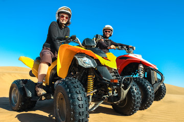 Quad driving people - happy smiling couple bikers in sand desert.
