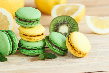 Green and yellow french macarons with kiwi, lemon and mint decorations