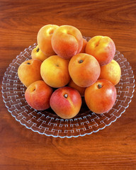 Fresh ripe apricots on plate on wooden background closeup