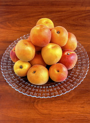 Fresh ripe apricots on plate on wooden background closeup