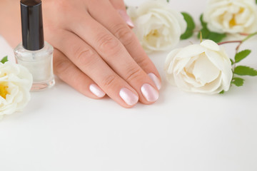 Fototapeta premium Cares about hands nails. Manicure beauty salon. Nails in pink color. Spring and summer gentle atmosphere with fresh and fragrant white roses on the table.