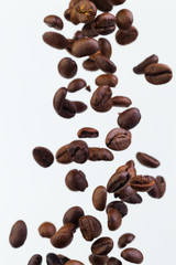 Falling grains of roasted coffee on a white background