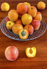 Fresh ripe apricots on plate on wooden background closeup