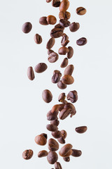 Falling grains of roasted coffee on a white background