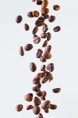 Zelfklevend Fotobehang Falling grains of roasted coffee on a white background © oleghz