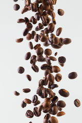 Falling grains of roasted coffee on a white background