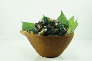 Stream mussels seafood with leaf in wooden bowl isolated white background