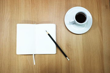 a notebook, a pencil and a cup of coffee on the desk