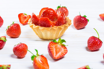 Tasty cake basket with strawberries and cream on a white wooden background with berries and leaves of fresh mint