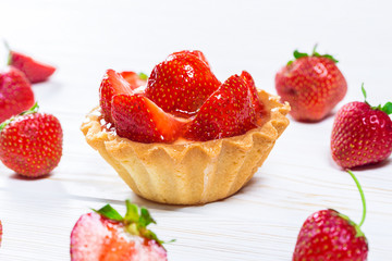 Tasty cake basket with strawberries and cream on a white wooden background with berries and leaves of fresh mint