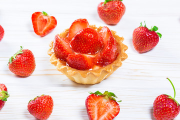 Tasty cake basket with strawberries and cream on a white wooden background with berries and leaves of fresh mint