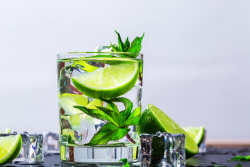Mojito cocktail with lime, ice cubes and mint in highball glass on a black background Copy space