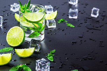 Mojito cocktail with lime, ice cubes and mint in highball glass on a black background Copy space