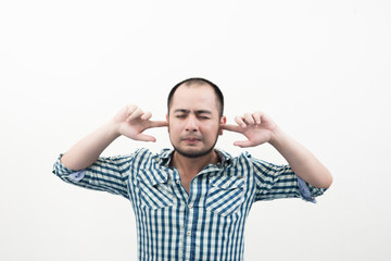 Portrait of young unhappy, stressed man covering his ears, looking up don't want to hear anything isolated white background.