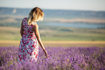 Fototapeta na wymiar Beautiful girl is walking on the lavender field