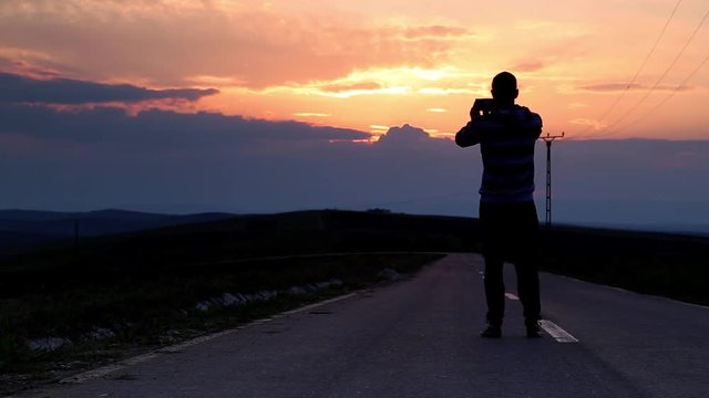 Young man takes pictures of sunset