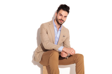 happy young smartcasual man sitting and fixing sleeve