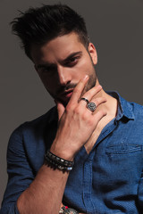 serious fashion man holding chin in his hand, thinking