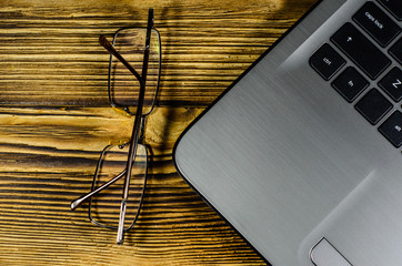 Laptop and glasses on wooden table. Top view