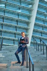 Businessman with a clipboard. Man standing on stairs. Best places to start business.