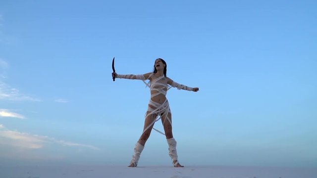 A live mummy of a woman with a dagger in her hand screaming in desert