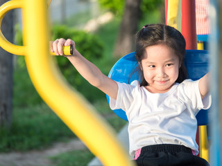 Fototapeta na wymiar Happy asian baby child playing on playground , exercise equipment in the garden