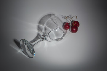 a glass of water and cherries on a white background.