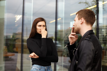Passive smoking concept. Confident handsome young male taking drag on cigarette, ignoring requests...