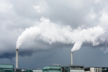 Industrial smoke emission from factory chimney under a stormy sky.