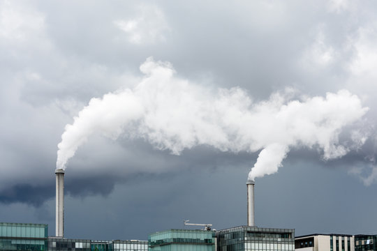 Industrial smoke emission from factory chimney under a stormy sky.