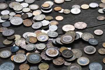 A pile of coins from different countries on a wooden table