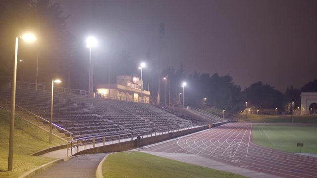 Lone Man Runs A Long Distance On A Track At Night In The Fog 